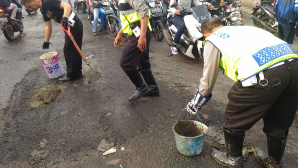 Personil Satlanas Polres Bandung berinisiatif menambal jalan berlubang di Jalan Raya Cinunuk, Desa Cinunuk, Kec Cileunyi, Kab Bandung,, Selasa (4/4). by bb-88